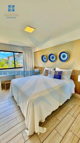 a bedroom with a large white bed with blue plates on the wall at La Fleur Collection Vacation Homes - Residence & Resort in Porto De Galinhas
