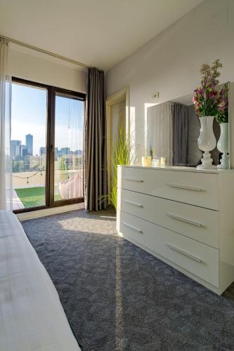 a bedroom with a white dresser and a large window at Downtown Floreasca Penthouse with Jacuzzi&Sauna in Bucharest