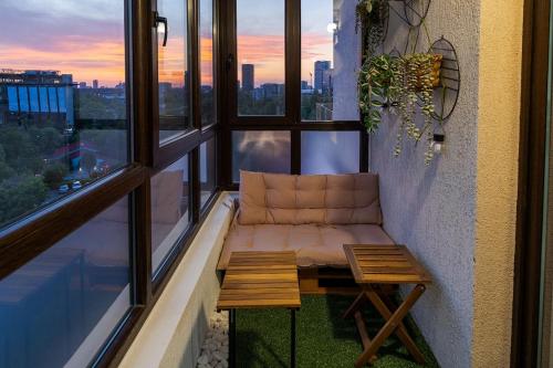 a balcony with a couch and a table and windows at Downtown Floreasca Penthouse with Jacuzzi&Sauna in Bucharest