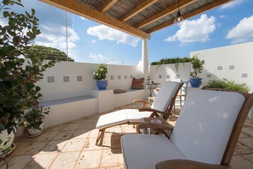 a terrace with white chairs and plants on a roof at Casa Fiammetta in Leuca