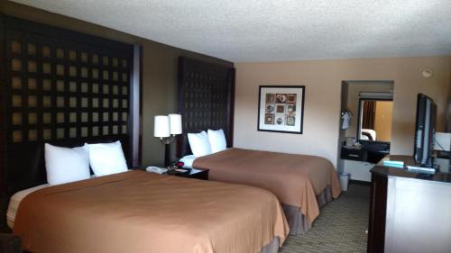a hotel room with two beds and a flat screen tv at Super 8 by Wyndham Atoka in Atoka