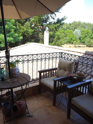 a porch with a couch and a table and an umbrella at The house on the road of Love in Vytina