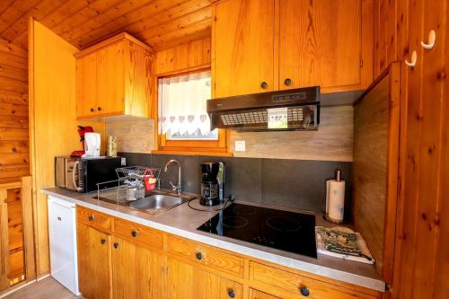 une cuisine avec un évier et une cuisinière four supérieur dans l'établissement Chalet Paradis, panoramic view, garden & terrace, à Xonrupt-Longemer