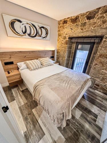a bedroom with a large bed and a stone wall at Casa do Pichón in Camariñas