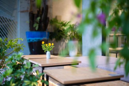 a table with a vase with yellow flowers on it at Tasme Dalat Signature in Da Lat