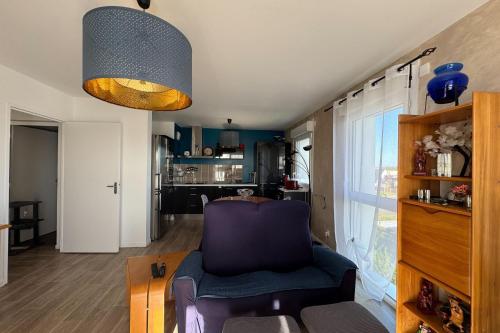 Il comprend un salon avec une chaise violette et une cuisine. dans l'établissement Apartment with balcony in Biéville-Beuville, à Biéville-Beuville