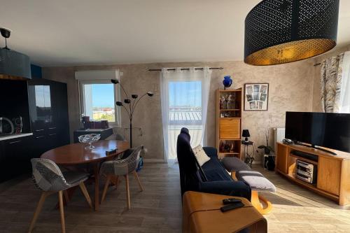 un salon avec une table, des chaises et une télévision dans l'établissement Apartment with balcony in Biéville-Beuville, à Biéville-Beuville