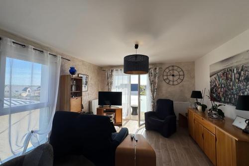 un salon avec un canapé, des chaises et une télévision dans l'établissement Apartment with balcony in Biéville-Beuville, à Biéville-Beuville