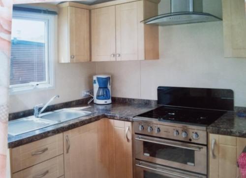 Il comprend une cuisine équipée d'une cuisinière. four supérieur à côté d'un évier dans l'établissement Mobil 6 Places direct sur la plage, à Camiers