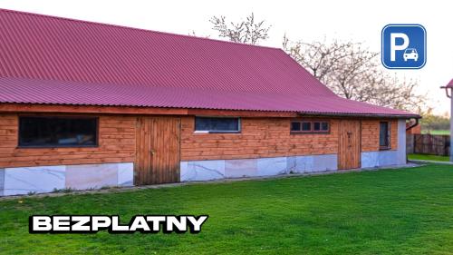 a building with a red roof on a green field at Agroturystyka Nielisz Zamość - Kwatery przy Skansenie in Nielisz