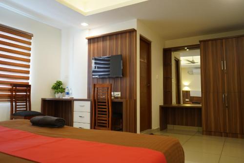a bedroom with a bed and a desk and a television at Royal Mansion Hotel in Cochin