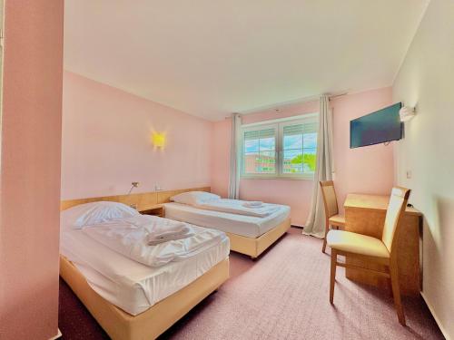 una habitación de hotel con dos camas y una silla en AR Boutique Hotel Heusenstamm, en Heusenstamm