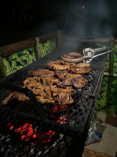 a bunch of meat cooking on a grill at Bush Adventure Guest House in Kasane