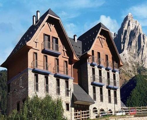 un grande edificio con una montagna sullo sfondo di Apartahotel Tres Quiñones a Sallent de Gállego