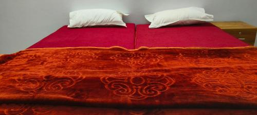 a red bed with two pillows on top of it at Royal Suites in Ernakulam