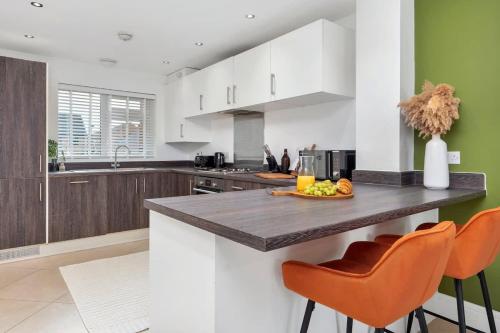 eine Küche mit weißen Schränken und einer Theke mit orangefarbenen Stühlen in der Unterkunft NEW Canalside House / 3 Bedroom House in Stoke-on-Trent in Stoke on Trent