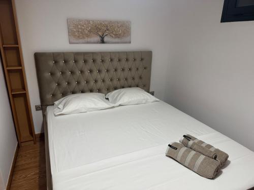 a bedroom with a white bed with a gray headboard at A little paradise in Rafina