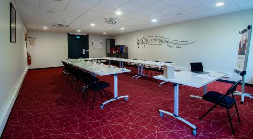 a conference room with tables and chairs and a white wall at Ibis Styles Toulouse Blagnac Aéroport in Blagnac