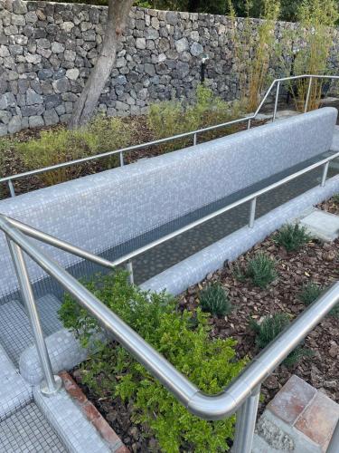 a metal bench sitting next to a stone wall at Hotel Pineta in Ischia