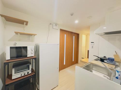 a kitchen with a refrigerator and a microwave at 阿久津ハイツ102 in Tokyo