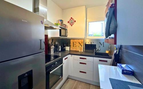 une cuisine avec des armoires blanches et un réfrigérateur en acier inoxydable dans l'établissement Appartement Colomba, à Calvi