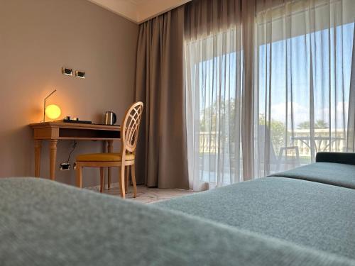 a bedroom with a desk and a bed and a window at Palace Hotel Desenzano in Desenzano del Garda