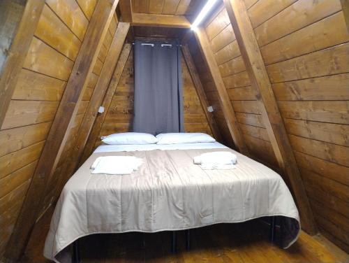 ein Bett in einem Holzzimmer mit zwei Handtüchern darauf in der Unterkunft Glamping Policoro Village in Policoro
