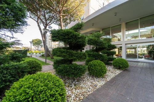 a garden in front of a building with bushes at Hotel Balance in Milano Marittima