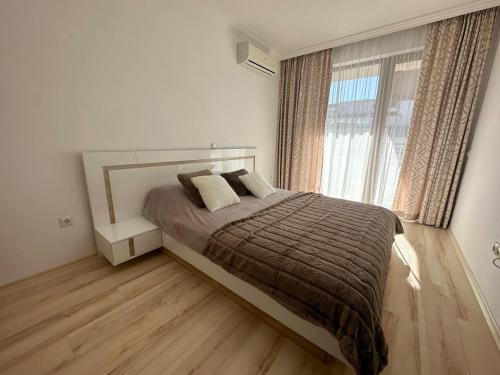 une chambre avec un lit et une grande fenêtre dans l'établissement Apartment in the complex Olymp, à Sveti Vlas