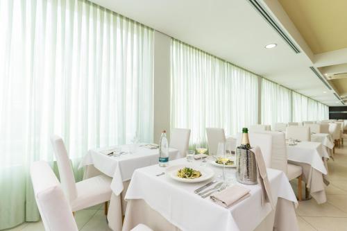 a dining room with white tables and white chairs at Hotel Balance in Milano Marittima