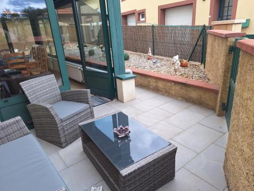 a patio with wicker chairs and a glass table at Chambre d'hôte au Grenier d'Abondance in Niderviller