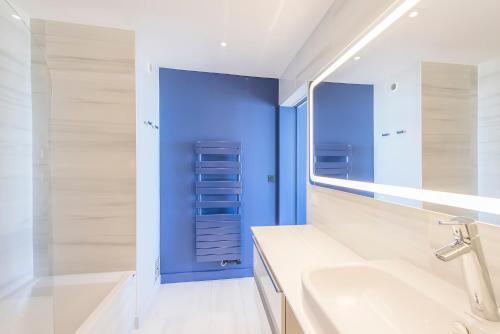 a bathroom with a white sink and a blue wall at Vue sur mer La Baule Victoria in La Baule