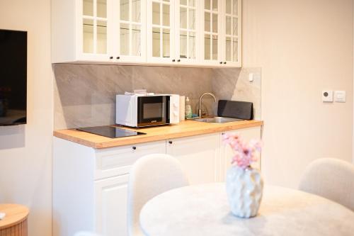 a kitchen with white cabinets and a table with a microwave at Kaptol 2 in Zagreb