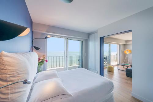 a bedroom with a white bed and a balcony at Vue sur mer La Baule Victoria in La Baule