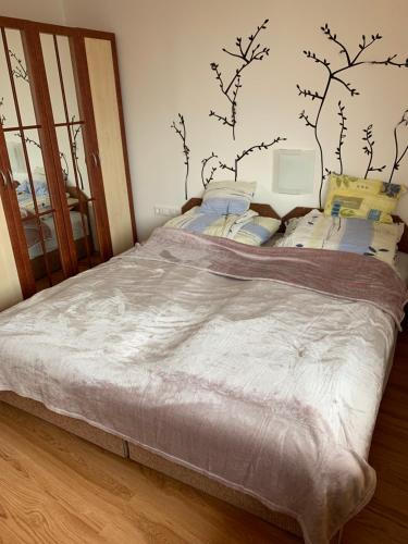 a bedroom with a large bed with branches on the wall at Hunor Apartmanok Napsugár in Balatonlelle