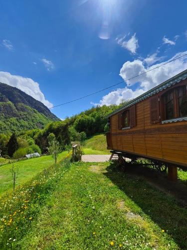 un wagon garé à côté d'un champ vert dans l'établissement Roulotte Ancolie, à Gèdre