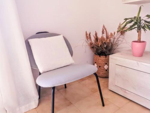 a white chair sitting in a room with plants at La casetta sulla spiaggia in La Caletta