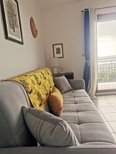 a living room with a gray couch and a window at La casetta sulla spiaggia in La Caletta