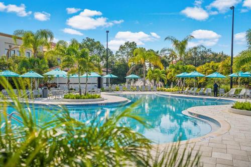 a swimming pool at a resort with blue umbrellas at Epic Universe New Listing, Family Vacation Townhome - 4011 in Orlando