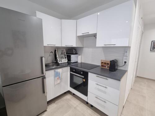 une cuisine avec des armoires blanches et un réfrigérateur en acier inoxydable dans l'établissement Tanit - Proche centre et plages - piscine, à Antibes