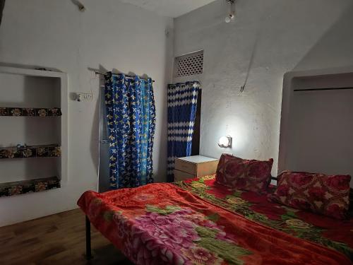 カジュラーホーにあるKhajuraho Dreams Homestayのベッドルーム(赤いベッド1台、青いカーテン付)