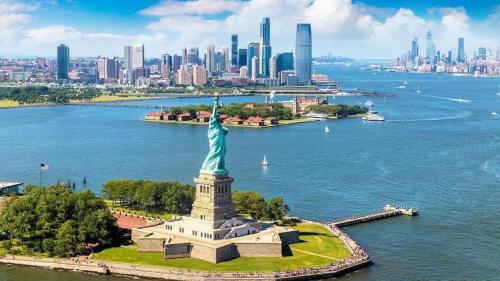 a statue of liberty on the water with a city in the background at The Mirage Stay 3 Bedroom Apt 20 Min to NYC in West New York