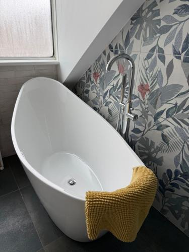 a white bath tub in a bathroom with a wall at Seaside Rentals Bournemouth - cosy 2BR, 4-6ppl, beach 5 min walk, park 2 cars, fast WiFi in Bournemouth