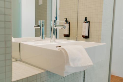 ein weißes Waschbecken in einem Badezimmer mit einem Spiegel in der Unterkunft Penthouse Deluxe I Dachterrasse I Parkplatz in Dresden