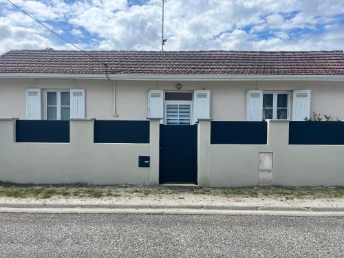 a white house with a blue door on a street at Villa clair logis in Andernos-les-Bains