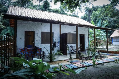 a small white house with a porch and a fence at Casa Muiraquitã Experiências Amazônicas in Santarém