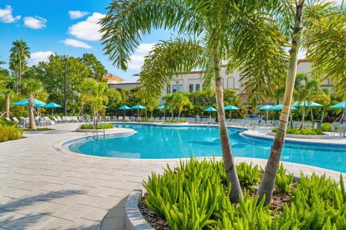 a resort swimming pool with palm trees and umbrellas at Epic Universe Lake View Condo, Vista Cay - 1005 in Orlando