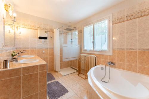 La salle de bains est pourvue de 2 lavabos, d'une baignoire et d'une fenêtre. dans l'établissement Villa Bellevue, à Vaison-la-Romaine