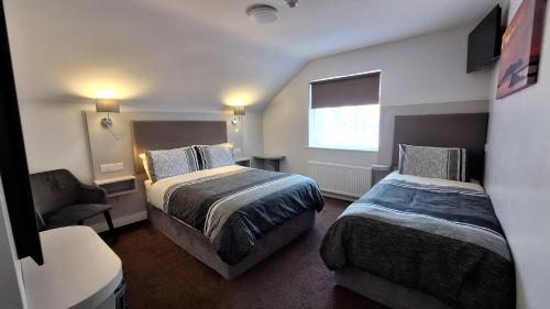 a hotel room with two beds and a chair at Murphy's Guesthouse in Dingle