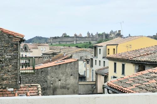 - une vue sur les toits des bâtiments avec un château en arrière-plan dans l'établissement Apartment with view on the city of Carcassonne, à Carcassonne